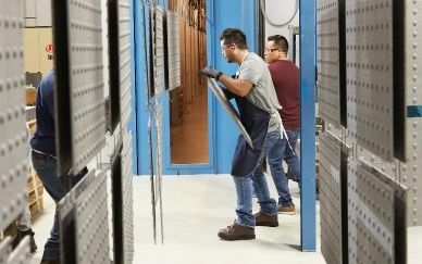 Workers wearing safety equipment prepare warning tiles for powder coating